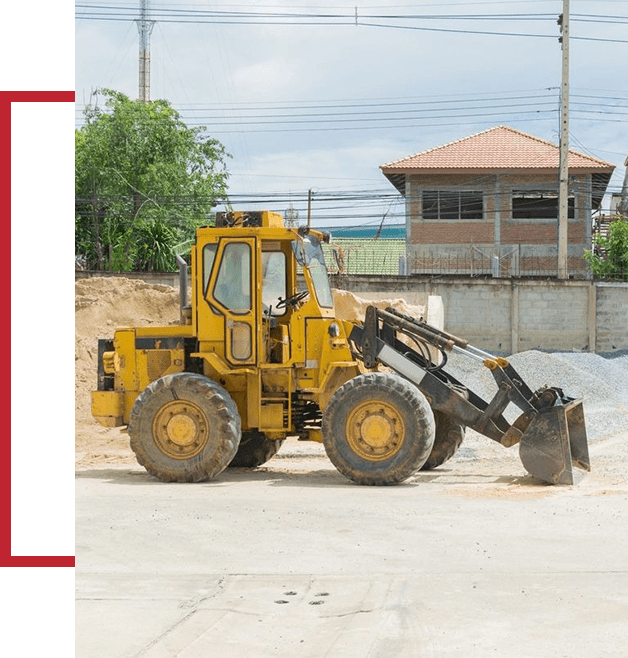 A yellow tractor is parked in the dirt.