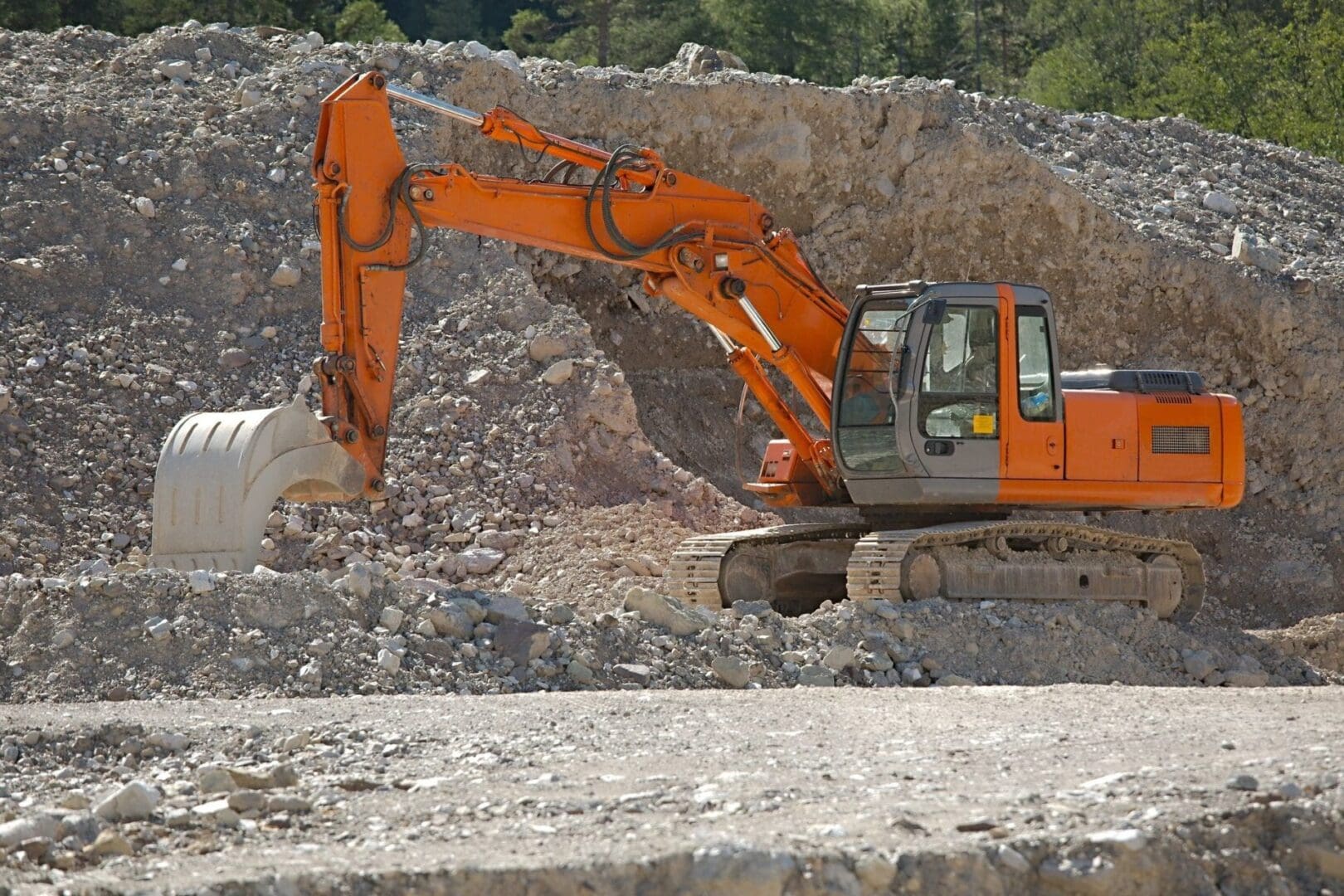 A large orange and white excavator is in the dirt.